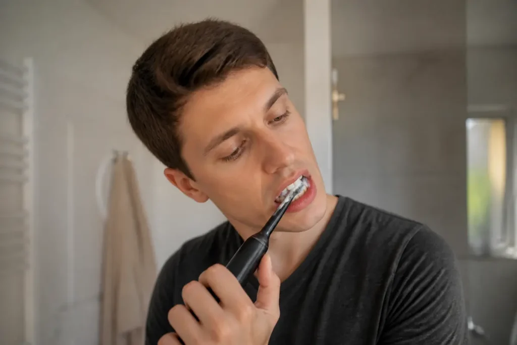 Homme utilisant une brosse à dents électrique pour un brossage des dents efficace et soigné