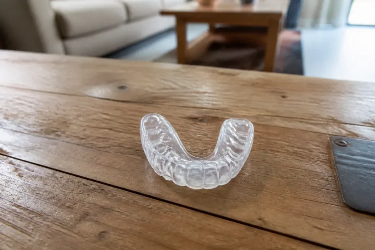 Gouttière dentaire contre le bruxisme posée sur une table en bois au salon